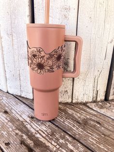 a pink coffee cup sitting on top of a wooden table