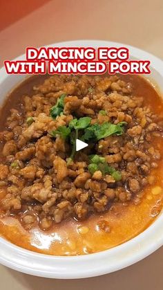 a white bowl filled with food on top of a wooden table and the words dancing egg with minced pork