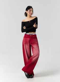 a woman in red pants and black top posing with her arms folded over her chest