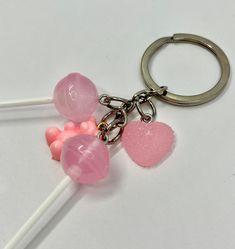 two candy lollipops on a white table with a heart shaped keychain