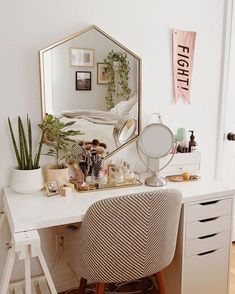 a white desk topped with a mirror next to a plant