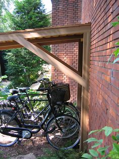 two bikes parked next to each other in front of a brick building with a wooden frame