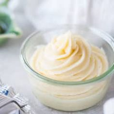 a glass bowl filled with whipped cream on top of a white table cloth next to silverware