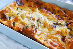 a casserole dish with cheese and other toppings in a white baking dish