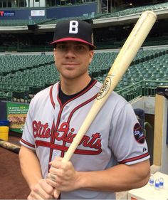 a man holding a baseball bat in front of an empty bleachers at a stadium