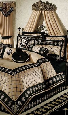 a bed with black and gold comforters in a bedroom next to two drapes