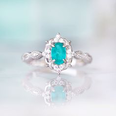 Gorgeous Vintage Inspired Neon Paraiba Tourmaline Ring Made of Solid Sterling Silver, Rhodium Plated (S925) Accented with Simulated Diamonds Center Stone: Paraiba Tourmaline Gemstone Creation: Lab-Created Stone Cut: Oval Color: Turquoise Gem size: 6.0 x 4.0 mm Carat Weight: 0.43 (approx.) Gemstone Origin: Brazil Can be made in solid gold and customized to a different gemstone. Please contact us if you have special requests. Handling time: 1-2 business days Free domestic shipping. Usually takes 2 Elegant Silver Turquoise Ring With Birthstone, Elegant Silver Turquoise Birthstone Ring, Emerald Cut Turquoise Jewelry For Wedding, Turquoise Emerald-cut Jewelry For Wedding, Turquoise Emerald Ring For Anniversary, Elegant Turquoise Emerald Ring In Sterling Silver, Fine Jewelry Turquoise Birthstone Ring For Anniversary, Elegant Turquoise Ring With Halo Setting For Anniversary, Vintage Emerald Ring For Promise