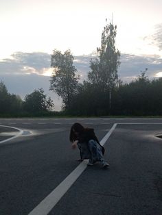 a person kneeling down on their skateboard in the street