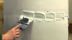 a man is painting the wall with white paint