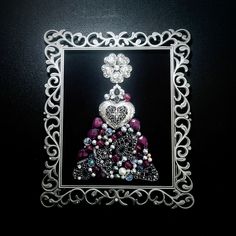 an ornate silver frame with a christmas tree made out of beads and other things on it