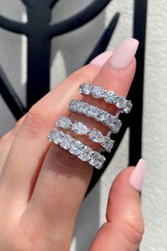 a woman's hand holding three rings with diamonds on them, and the middle one is