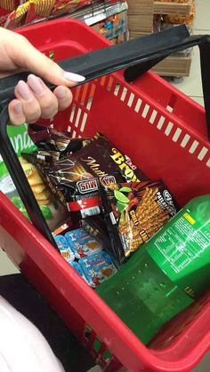 a person holding a shopping basket full of snacks