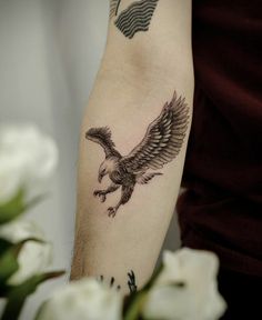 an eagle tattoo on the right arm and left arm, with flowers in the background