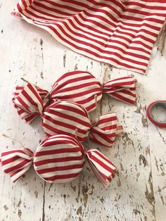 red and white striped fabric with scissors next to it on a wooden surface, including two pieces of cloth that have been cut in half