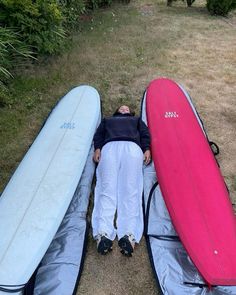 a man laying on the ground with three surfboards next to him and his head resting on one another