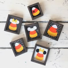 four framed mickey mouse magnets on a white wooden table with black and yellow polka dots