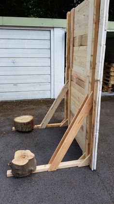 a wooden structure sitting on top of a parking lot next to a pile of logs