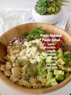 a wooden bowl filled with pasta salad on top of a table