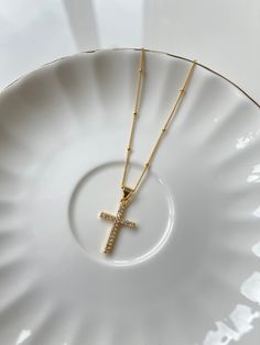 A meaningful symbol, the Cross Pendant Necklace is lined with gems and shines to bring new life to a classic. The cross brings maximum shine with a delicate touch meant to be worn everyday, layered or on its own. Suspended on our dainty beaded golden chain. Details: The length of the Cross Pendant Necklace is 16 inches with an additional 2.5-inch extender chain to easily adjust the length, providing a total adjustable length of up to 18.5 inches. The pendant measures 15 mm in diameter. SHIPPING Gold Plated Cross Necklace With Delicate Chain, Dainty Crucifix Cross Necklace With Delicate Chain, Gold-plated Cross Necklace With Adjustable Chain, Gold Plated Cross Necklace With Adjustable Chain, Dainty Gold Crucifix Cross Necklace, Gold Crucifix Cross Necklace With Delicate Chain, Golden Chain, Cross Pendant Necklace, The Cross