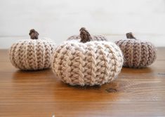 three knitted pumpkins sitting on top of a wooden table