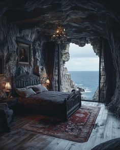 a large bed sitting inside of a cave next to the ocean