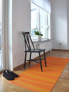 a chair sitting on top of a wooden floor next to a yellow and white rug