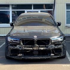 the front end of a car that is parked in a parking lot next to a building