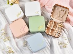 four personalized jewelry boxes sitting on top of a white sheet with flowers in the background