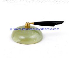 a green jade with a black handle on a white table top, next to a gold - plated knife