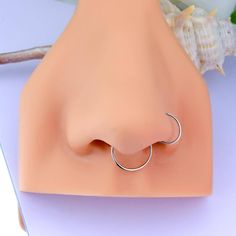 a fake nose ring is shown on top of a plastic head with seashells in the background