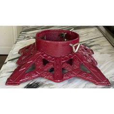 a red leather belt with metal buckles on top of a marble tablecloth covered surface