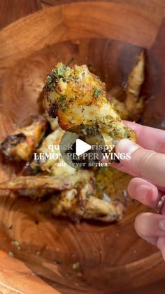 someone is holding up a piece of food in a wooden bowl with broccoli on it