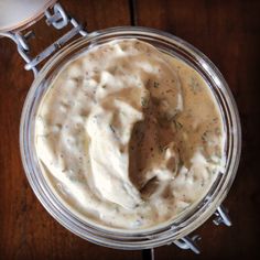 a glass jar filled with white sauce on top of a wooden table