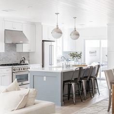 a kitchen and dining room with white cabinets, marble counter tops and an island in the middle