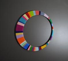 a circle made out of colored yarn sitting on top of a gray wall next to a white wall