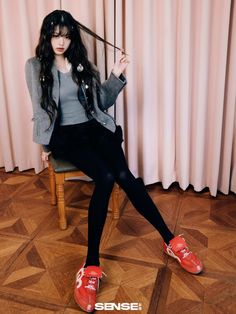 a woman sitting on top of a wooden chair holding an umbrella over her head and wearing red shoes