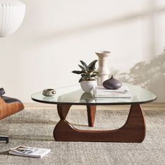 a living room with a chair, table and vases on the carpeted floor