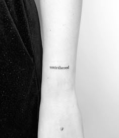 a black and white photo of a person's arm with the word untethered tattooed on it