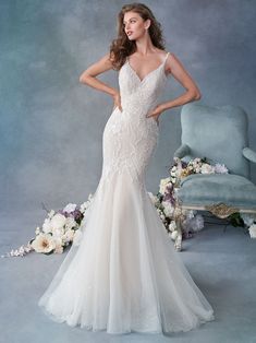 a woman in a white wedding dress standing next to a chair and flower bouquets