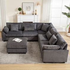 a living room with a large gray sectional couch and footstool on the floor