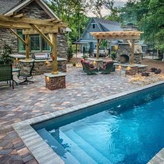 a backyard with a swimming pool, patio and pergolated seating area next to it