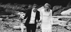 black and white photo of bride and groom walking on the beach with flowers in their hair