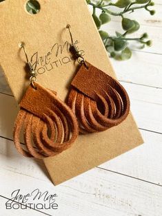 two pairs of brown leather earrings sitting on top of a card