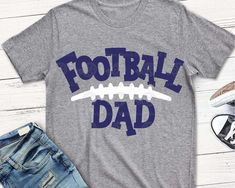 a football dad t - shirt with the words football dad printed on it, next to jeans and sneakers