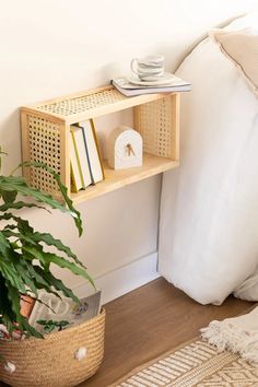 a wooden shelf with books and magazines on it next to a plant in a wicker basket