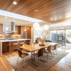 a kitchen and dining room with wood flooring in the middle, an island table surrounded by chairs