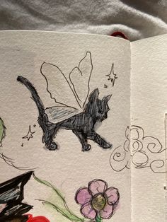 an open book with drawings on it and flowers in the pages, including a cat