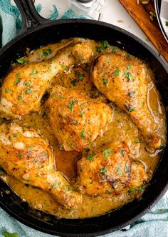 a skillet filled with chicken covered in gravy and garnished with parsley