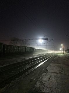 train tracks in the fog at night with street lights and power lines on either side