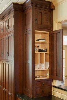 an armoire with wooden doors and drawers in a home office area that also has black marble counter tops